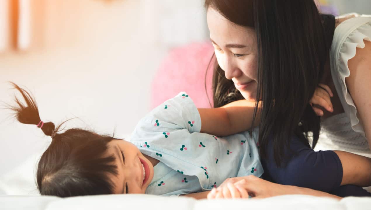 Mother playing with child on bed